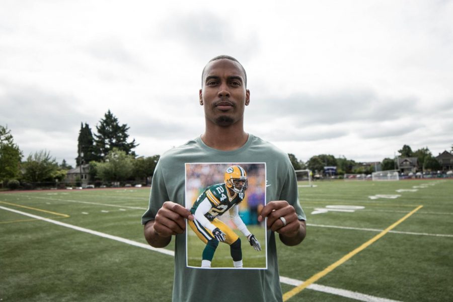 Coach Joey Thomas poses with an old photo of himself playing for the Packers.