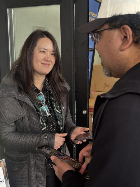 Seattle School Board Director Vivian Song sells Girl Scout cookies to a shopper outside a grocery store in north Seattle. (Rafael Brewer/Garfield Messenger)